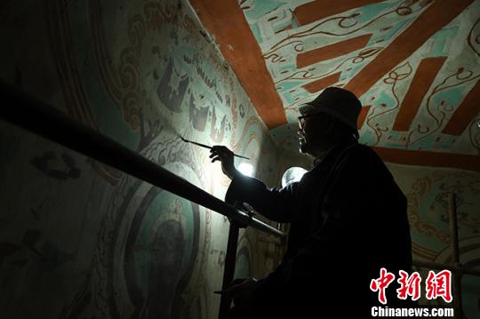 图为85岁的李云鹤打开灯,戴着老花镜开始修复工作。 杨艳敏 摄