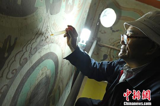 图为李云鹤拿着改良后的医用注射器将蒸馏水注入壁画“细如发丝”的缝隙。 杨艳敏 摄